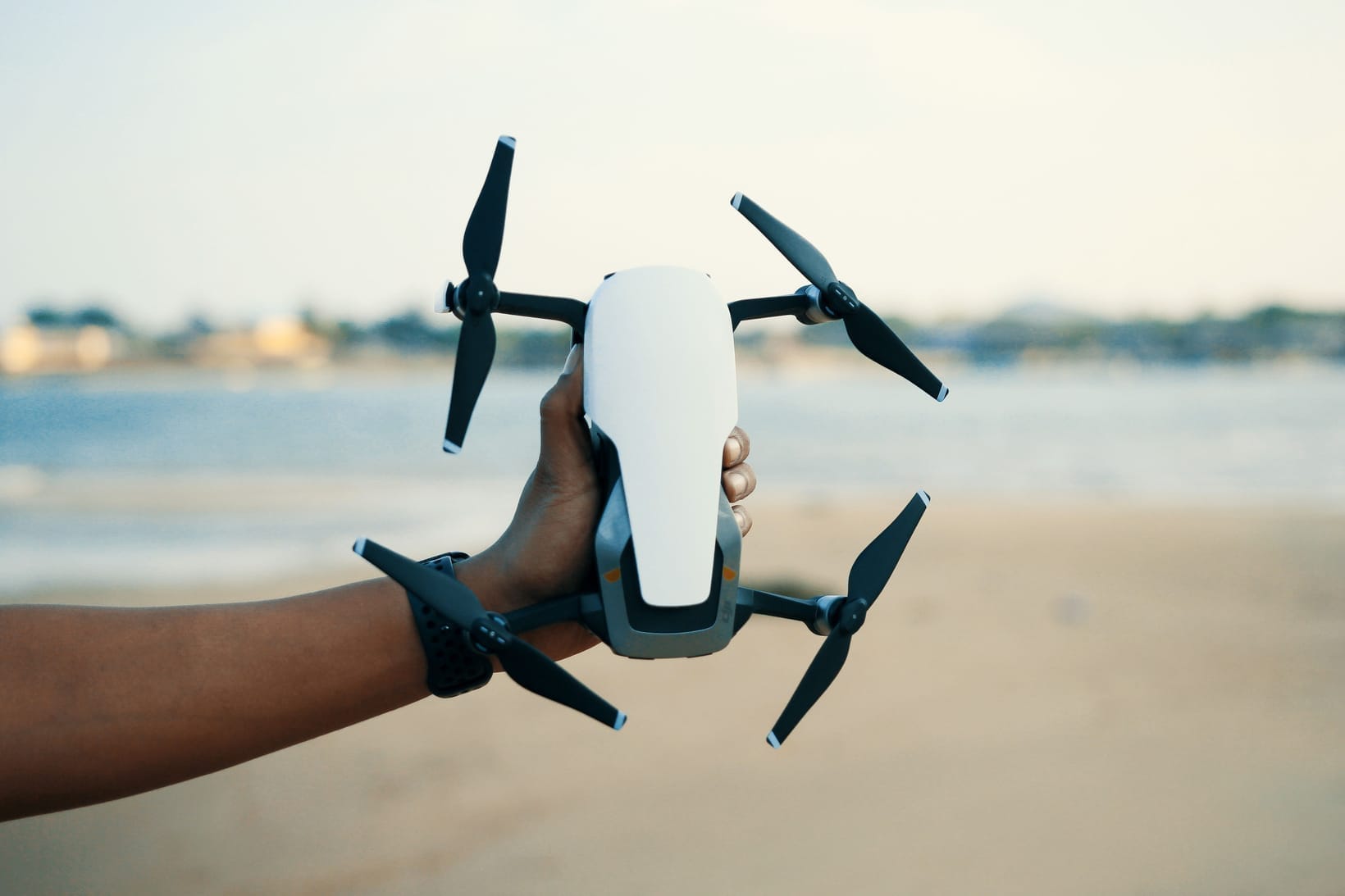 A folding camera drone held in an outstretched hand